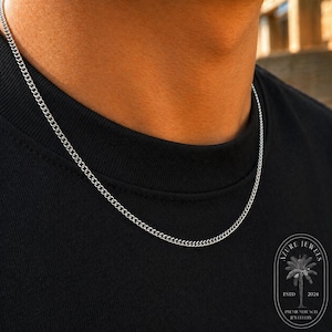 May include: A silver-toned curb chain necklace worn against a black t-shirt. In the bottom right corner, a logo features a palm tree graphic with the text AZURE JEWELS ESTD 2024 PREMIUM BEACH JEWELLERY.