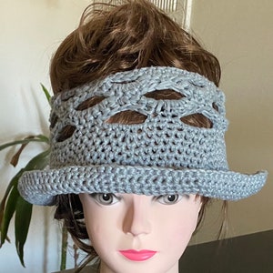 May include: A gray crocheted hat with a wide brim and a lacy design around the crown.