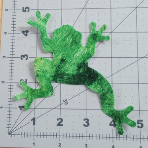 May include: Green fabric frog applique with a mottled green and yellow pattern. The frog is approximately 4 inches long and 3 inches wide.