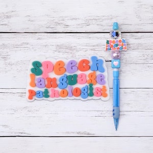 May include: A white background with a blue pen and a white sign that says "Speech Language Pathologist" in colourful letters.