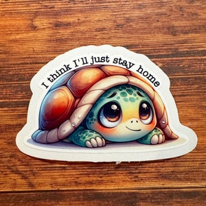 May include: A sticker featuring a cartoon turtle with big eyes, peeking out from its shell. The turtle is green and brown with a light blue belly. The sticker has the text "I think I'll just stay home" around the turtle.