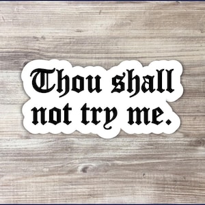 May include: White sticker with black text that reads "Thou shall not try me."