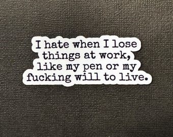 May include: A white sticker with black text that reads: "I hate when I lose things at work, like my pen or my fucking will to live." The sticker is on a dark gray background.