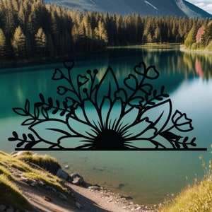 May include: Black and white silhouette of a floral design with a large flower in the center. The design is set against a background of a lake and mountains.