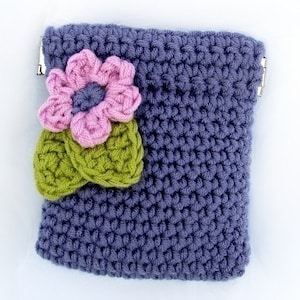 May include: A small crocheted purse with a flower design. The purse is a dark purple color and the flower is pink with green leaves.