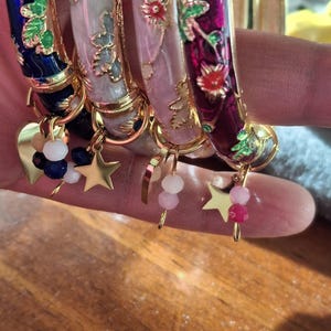 bracciale rigido a molla con smalto colorato e piccolo motivo floreale, ciondoli a forma di cuore o stella in acciaio inossidabile e perline sfaccettate