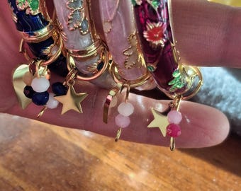 rigid spring bangle bracelet with colorful enamel and small flower motif, stainless steel heart or star charms, and faceted beads