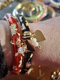 rigid spring bangle bracelet with colorful enamel and small flower motif, stainless steel heart or star charms, and faceted beads product logo