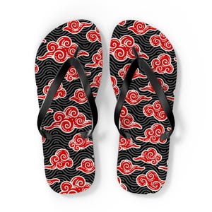 Peut inclure: Une paire de tongs avec une lanière noire et un motif de nuages noirs et rouges. Le motif présente des nuages rouges avec des contours blancs sur un fond noir avec des lignes grises en forme de vagues.
