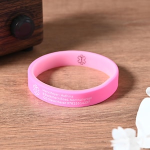 Könnte beinhalten: Rosa Silikon-Armband mit medizinischer Warnung mit weißem Text. Der Text lautet "Mary Meyer - Asthma, B-Blackthorn Road, Northallerton, ICE: Steve Meyer 07825514337".