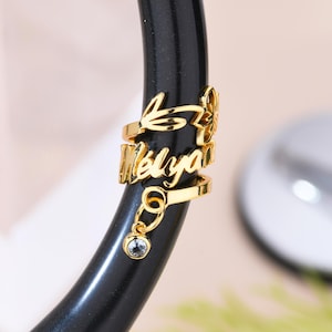 May include: Gold stethoscope charm with the name "Melyan" and a small crystal charm hanging from it.