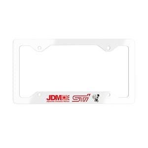 Könnte beinhalten: Ein weißer Kennzeichenrahmen mit dem Text "JDM" und einer Grafik der aufgehenden Sonne in Rot. Der Rahmen zeigt auch die Buchstaben "STI" in Rot und eine kleine Panda-Grafik. Der Text "Japanese Domestic Market" steht darunter.