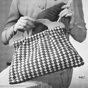 May include: A black and white crocheted bag with a checkered pattern. The bag has two wooden handles and is being held by a person.