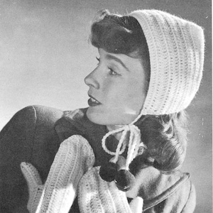 Może przedstawiać: Czarno-białe zdjęcie kobiety w białym, dzianym na szydełku kapeluszu i pasujących do niego rękawiczkach z pomponami. Kapelusz ma sznurki, które są zawiązane pod jej brodą.