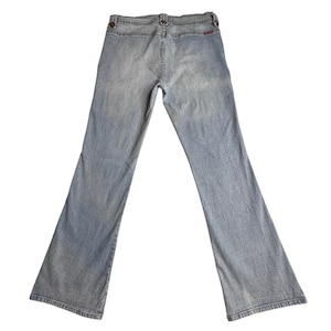 Puede incluir: Vaqueros de mezclilla azul claro con diseño de pierna acampanada. Los vaqueros presentan un estilo clásico de cinco bolsillos, trabillas para el cinturón y cierre de botón y cremallera. La vista trasera muestra los bolsillos y la etiqueta de la marca.