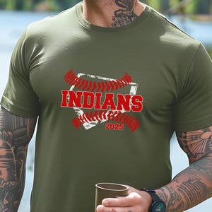 May include: A green t-shirt with a white baseball diamond graphic and red stitching. The text "INDIANS" is in red letters and the year "2025" is below the diamond.
