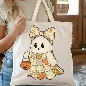 Pode incluir: Uma sacola branca com um personagem de fantasma de desenho animado usando um vestido de retalhos e um grande la&ccedil;o. O fantasma segura um balde de ab&oacute;bora. O design incorpora cores de outono como laranja, amarelo e marrom, perfeito para o Halloween.