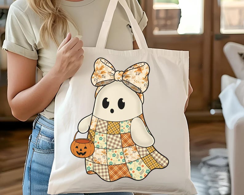 Pode incluir: Uma sacola branca com um personagem de fantasma de desenho animado usando um vestido de retalhos e um grande la&ccedil;o. O fantasma segura um balde de ab&oacute;bora. O design incorpora cores de outono como laranja, amarelo e marrom, perfeito para o Halloween.