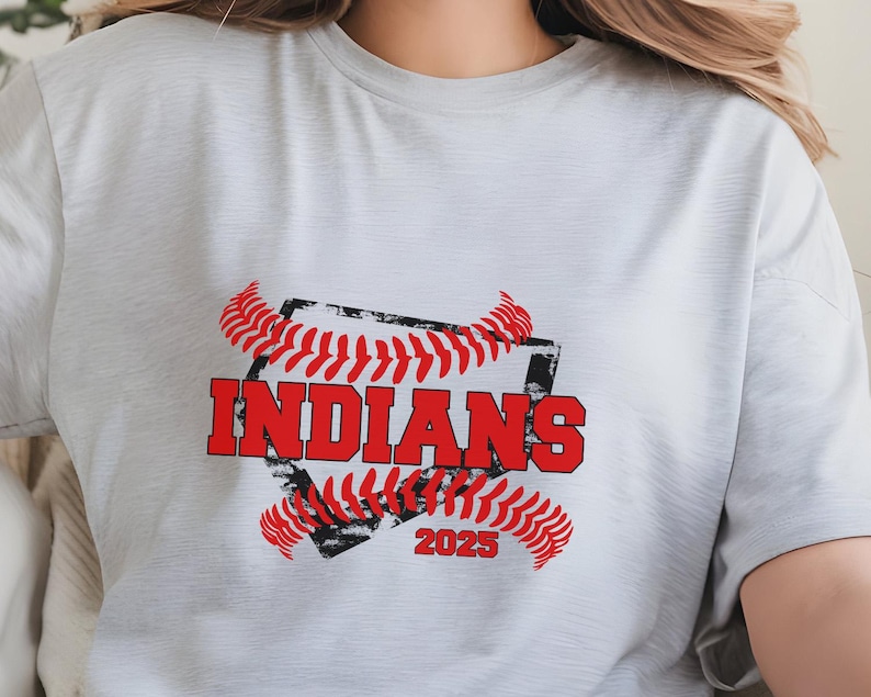 May include: A white t-shirt with a red and black baseball graphic. The graphic features a baseball diamond with the word "INDIANS" in red text and the year "2025" in black text.
