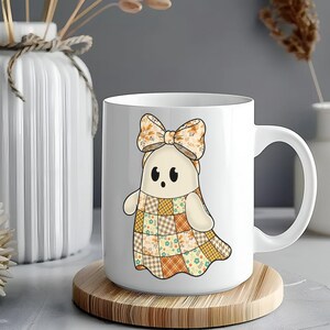 Pode incluir: Caneca de cer&acirc;mica branca com um personagem de desenho animado fantasma com um vestido de retalhos e um la&ccedil;o. O fantasma tem uma express&atilde;o amig&aacute;vel. A caneca est&aacute; em uma base de madeira.