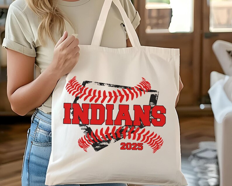 May include: White canvas tote bag with a red and black baseball graphic. The graphic features a baseball with red stitching and the text "INDIANS 2023".