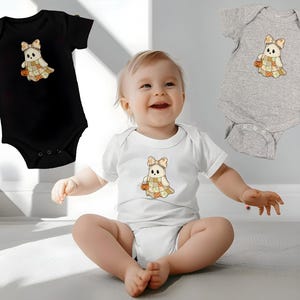 Pode incluir: Tr&ecirc;s bodies de beb&eacute; em preto, branco e cinzento. Cada body apresenta um desenho de fantasma de desenho animado com um la&ccedil;o, um vestido de patchwork e uma ab&oacute;bora. O beb&eacute; na imagem est&aacute; a usar um body branco com o mesmo desenho de fantasma.