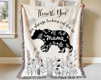 May include: A cream-colored woven throw blanket with a black silhouette of a bear with floral details. The text "Thank You for always looking out for us mama" is printed on the blanket.
