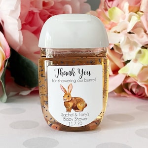 K&ouml;nnte beinhalten: Eine durchsichtige Plastikflasche mit Handdesinfektionsmittel, einem wei&szlig;en Deckel und einem runden Etikett. Das Etikett zeigt ein braunes Kaninchen und den Text "Thank You for showering our bunny! Rachel & Tony's Baby Shower 11.7.20".