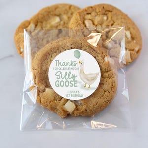 May include: A clear plastic bag filled with cookies and a round sticker that says "Thanks for celebrating our Silly Goose Emma's 1st Birthday" with a cartoon goose wearing a party hat and holding a balloon.