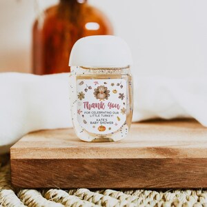 May include: A clear hand sanitizer bottle with a white cap. The label reads "Thank you" with a turkey illustration and text: "For celebrating our little turkey! Kate's baby shower."