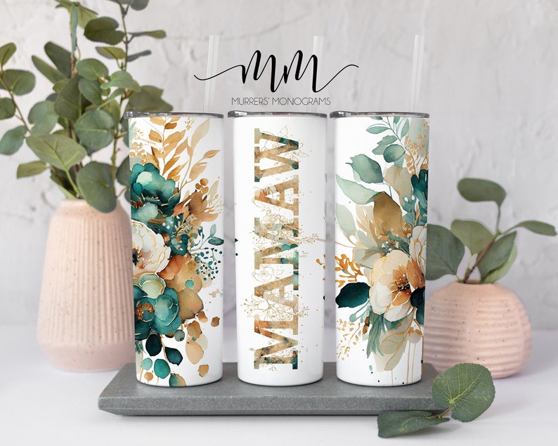 May include: Three white stainless steel tumblers with a floral design in shades of teal, gold, and brown. The tumblers have a gold glitter design with the name "MATTHEW" on the middle tumbler.