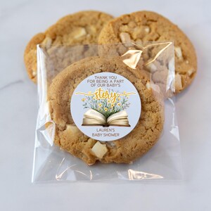 May include: A clear plastic bag filled with cookies and a round sticker that says "Thank you for being a part of our baby's story. Lauren's Baby Shower". The sticker has a yellow and white floral design with an open book in the center.
