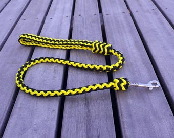May include: A black and yellow braided dog leash with a silver clip.