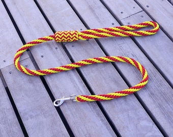 May include: A red and yellow braided dog leash with a silver clip.