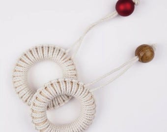 May include: Two white rope rings with a red and a brown wooden bead on each end of the rope.