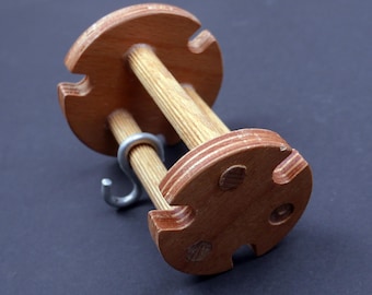 May include: A wooden yarn swift with two dowels and a metal hook. The swift is made of plywood and has a natural wood finish.