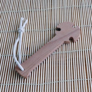 May include: A wooden tool with a handle and a unique shape at the end, resembling a hammer or a wrench. The tool is tied with a white string.