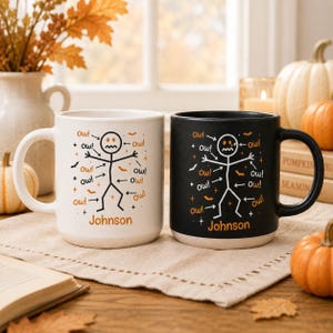 Könnte beinhalten: Ein weißer Keramikbecher und ein schwarzer Keramikbecher, beide mit einer Strichmännchen-Grafik, auf die Pfeile mit der Aufschrift Ow! zeigen, sowie kleinen Fledermaus-Silhouetten und dem Namen Johnson in orangefarbenem Druck.