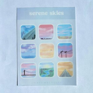 May include: A sheet of stickers with the text "serene skies" at the top. Each sticker features a different landscape scene, including mountains, sunsets, and bridges, in pastel colors. The stickers are square with rounded corners.