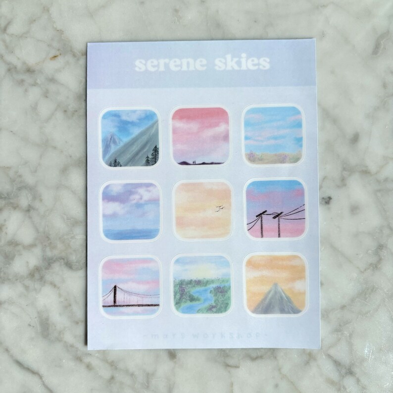 May include: A sheet of stickers with the text "serene skies" at the top. The stickers feature square illustrations of various sky scenes, including mountains, sunsets, and landscapes. The color palette includes blues, pinks, and oranges.