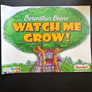 Może przedstawiać: Kolorowa ilustracja z Berenstain Bears. Obraz przedstawia duże zielone drzewo ze słowami "WATCH ME GROW!" w kolorze pomarańczowym. Widoczny jest również domek na drzewie z różowym dachem i logo Hormel Kids' Kitchen.