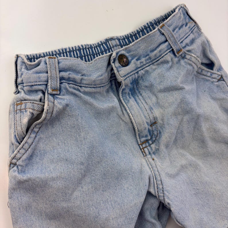 Puede incluir: Vaqueros de mezclilla azul claro con cierre de bot&oacute;n y cintura. Los vaqueros tienen un corte holgado y est&aacute;n hechos de una tela suave y c&oacute;moda.