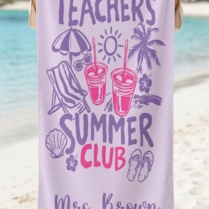 May include: A lilac beach towel with the text "Tired Teachers Summer Club" in purple and pink. The towel has illustrations of beach items, including a parasol, sunglasses, drinks, a deckchair, and Mrs. Brown's name.