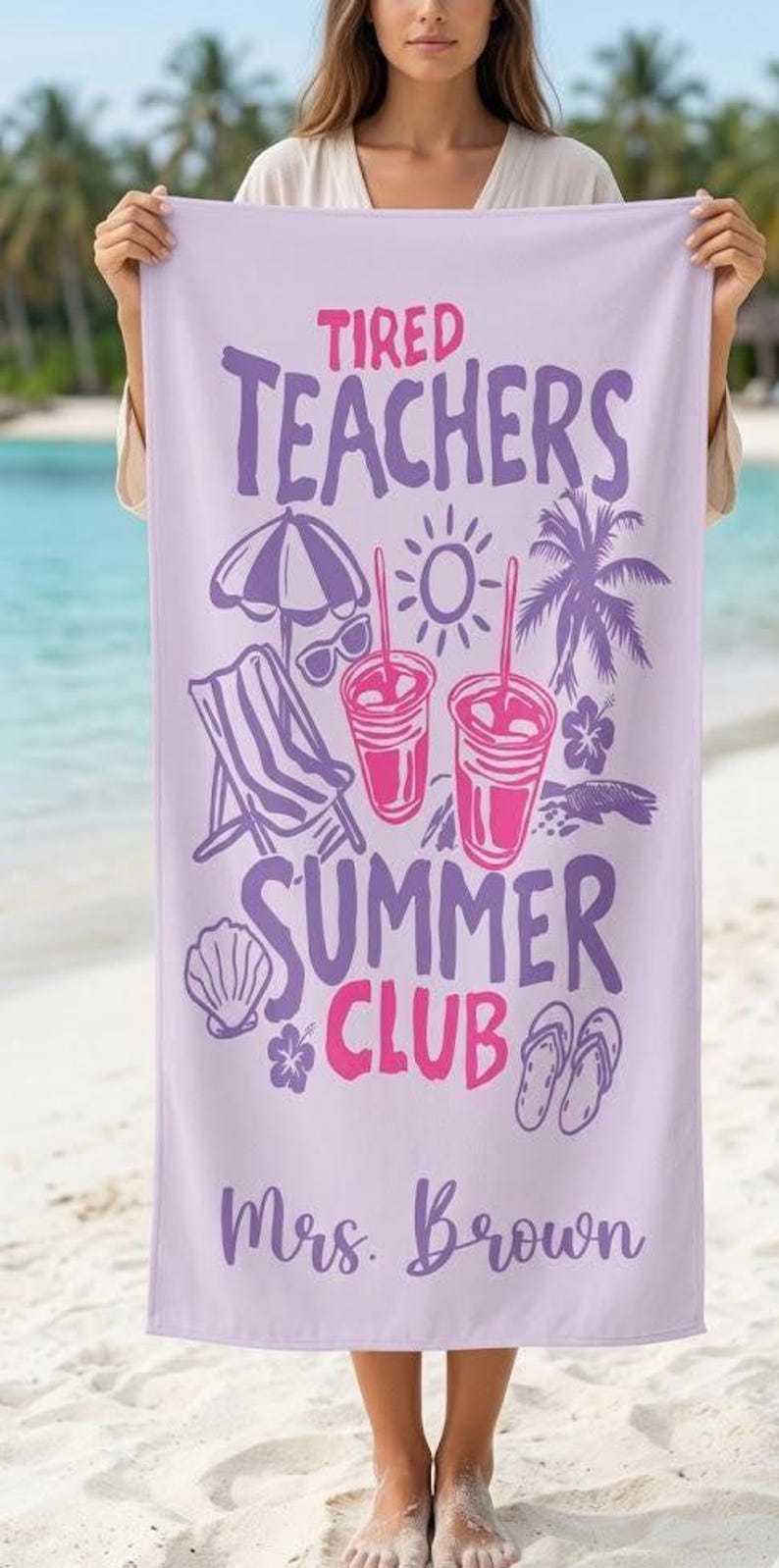 May include: A lilac beach towel with the text "Tired Teachers Summer Club" in purple and pink. The towel has illustrations of beach-themed items, including a parasol, sunglasses, a deckchair, drinks, and Mrs. Brown's name.