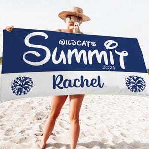 May include: A navy blue and white beach towel with the word "Summit" in large white letters. The towel also features the name "Rachel", the year "2026", and two pom-pom graphics. The towel is held up on a beach.