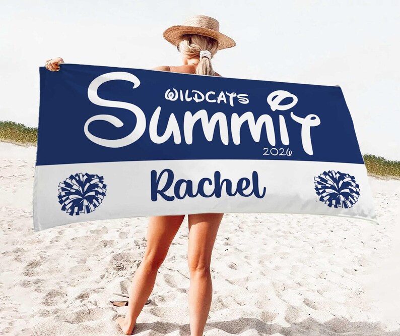 May include: A navy blue and white beach towel with the word "Summit" in large white letters. The towel also features the name "Rachel", the year "2026", and two pom-pom graphics. The towel is held up on a beach.