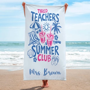 May include: White beach towel featuring blue and pink text and graphics. The towel displays "Tired Teachers Summer Club" with illustrations of a beach chair, sunglasses, drinks, and a palm tree. The name "Mrs. Brown" is printed at the bottom.