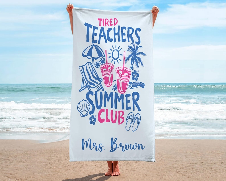 May include: White beach towel featuring blue and pink text and graphics. The towel displays "Tired Teachers Summer Club" with illustrations of a beach chair, sunglasses, drinks, and a palm tree. The name "Mrs. Brown" is printed at the bottom.