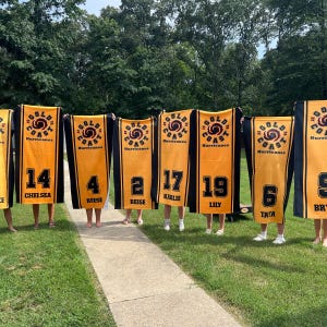 Peut inclure: Plusieurs serviettes de sport dor&eacute;es et noires avec le texte "Gold Coast Hurricanes" et des num&eacute;ros de joueurs. Chaque serviette affiche un num&eacute;ro et un nom de joueur diff&eacute;rents, dont 14 Chelsea, 4 Reese, 2 Reese, 17 Karlie, 19 Lily et 6 Tata.