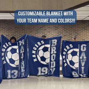 May include: Navy blue customizable blankets with white soccer ball graphics and team names. The blankets have the text "CUSTOMIZABLE BLANKET WITH YOUR TEAM NAME AND COLORS!!!". Each blanket has a different name and number.